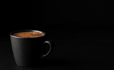 A cup of espresso with foam. Black stone background. Copy space for text. Close-up, shallow depth of field. Morning hours waiting for coffee.