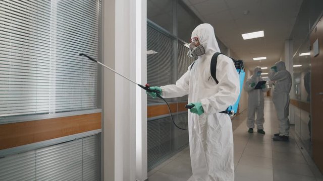 Specialists disinfecting business center with chemical detergents against 2019-ncov