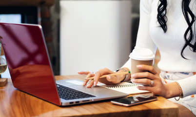 Business woman using laptop to searching information from internet and holding coffee cup to drink