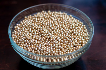Close up of little golden balls in a clear transparent bowl.