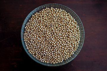 Close up of little golden balls in a clear transparent bowl.