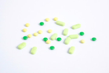 Different color pills. Green and yellow tablets scattered on white background. Medicine for prevention of the spread of coronavirus. Coronavirus protection