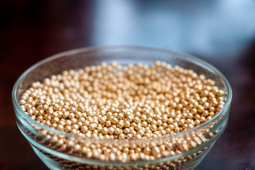 Close up of little golden balls in a clear transparent bowl.