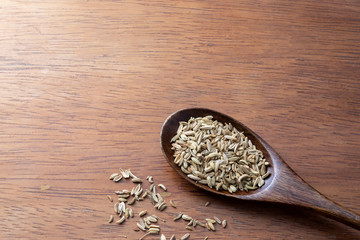 Cumin seed, spice, in wooden spoon on rustic wood background, cooking preparation