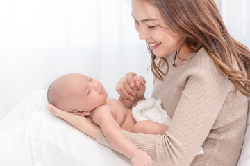 Close up beautiful young asian mother holding her newborn one month baby sleep on herlap. Healthcare and medical love asia woman lifestyle mother's day concept.