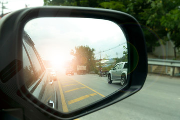 Side view of car mirror traffic of rear-end vehicles on the road with yellow line.