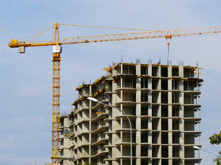Crane near building. Concrete building under construction.