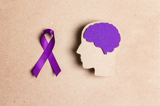 Purple awareness ribbon and brain symbol on a brown background. Epilepsy disease or Alzheimer disease awareness world day.