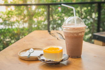 Orange cake and cold coco on wooden table and nature background, selection focus at cold coco.