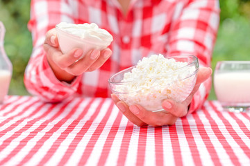 Girl farmer in red checkered shirt holds out bowl of cottage cheese