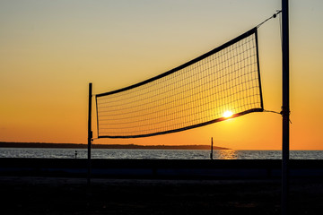 Sillhouette of a volleyball net against sunset on the beach