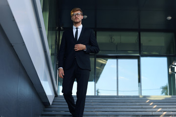 Successful young businessman walking down the stairs outside the office building.