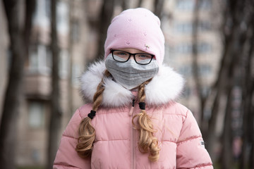 A child in a medical mask walks down the street