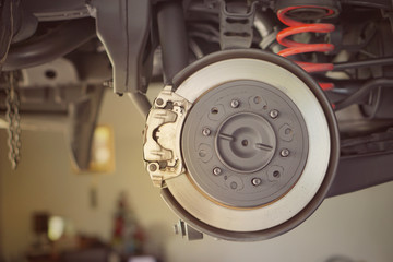  car brake part at garage,car brake disc without wheels.Disk brake and car disk brake system service concept - Car disk brake pad replacement service by hand of mechanic man in car garage.Close up.