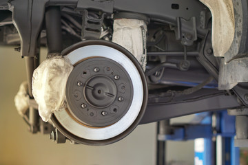 car brake part at garage,car brake disc without wheels.Disk brake and car disk brake system service concept - Car disk brake pad replacement service by hand of mechanic man in car garage.Close up.