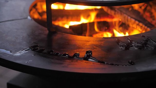 slow motion. fire is burning on the charcoal grill. man wipes surface of grill
