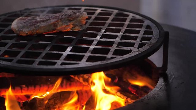 slow motion. fried steak on the charcoal grill. Chef turns the meat. close-up