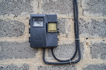 electric meter hanging on a stone wall