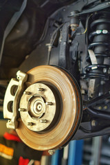 car brake part at garage,car brake disc without wheels.Disk brake and car disk brake system service concept - Car disk brake pad replacement service by hand of mechanic man in car garage.Close up.