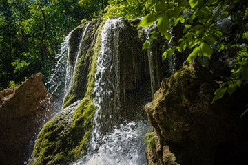 Fototapeta na wymiar A beautiful waterfall deep in the forest, steep mountain adventure in the rainforest.