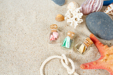 Fototapeta na wymiar message in a bottle, sea shells and pebbles on sand