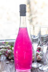 Sparkling brilliant raspberry drink. Champagne in two glasses stands on a wooden table with ice....