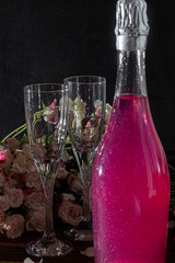 Sparkling brilliant raspberry drink. Champagne in two glasses stands on a wooden table with ice....