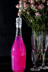 Sparkling brilliant raspberry drink. Champagne in two glasses stands on a wooden table with ice....