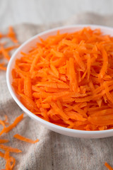 Shredded carrots in a white bowl, side view. Close-up.