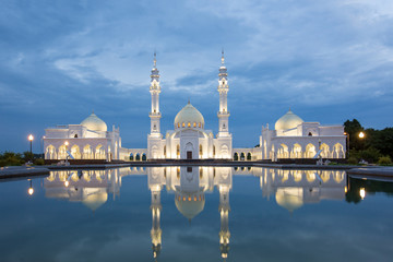 Beautiful White Mosque in Bolgar is reflected in the water against the evening sky with light