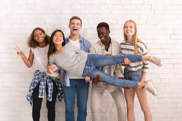 Joyful international group of friends posing over white wall
