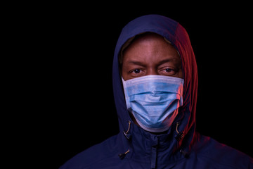 Coronavirus, African American man with protective mask, looking at the camera. COVID-19 concept. Studio shot on black background with copyspace.