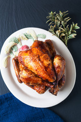 Food concept homemade Roasted, Grilled Whole organic chicken on white ceramic plate with black slate ston board background