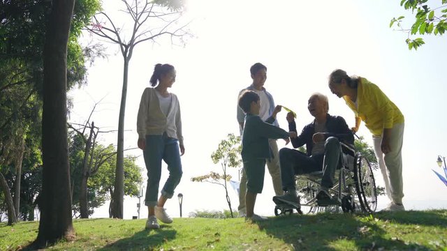 three generation asian family enjoying outdoor activity in park