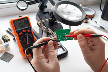 engineer makes measurements on the board with a multimeter