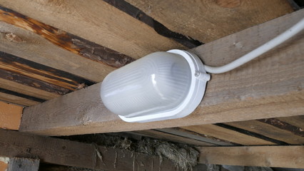 Fototapeta na wymiar Lamp on a wooden beam in the barn