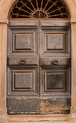 Detail of old timber door with arched window over the door in a building in Lucca, Italy