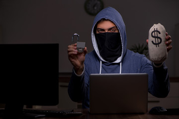 Male hacker hacking security firewall late in office