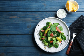 Tasty salad with Brussels sprouts served on blue wooden table, flat lay. Space for text
