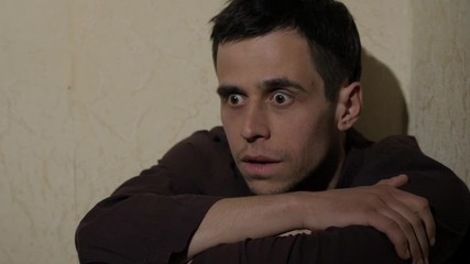 Man with persecution mania sitting near the wall