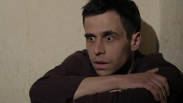 Man with persecution mania sitting near the wall