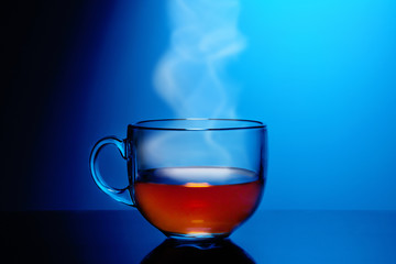 Cup of hot steaming tea on a blue background