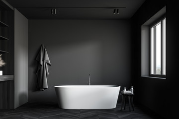 Fototapeta na wymiar Dark gray bathroom with tub and wooden shelves