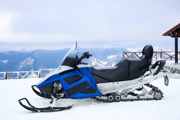 Modern snowmobile on hill at mountain ski resort