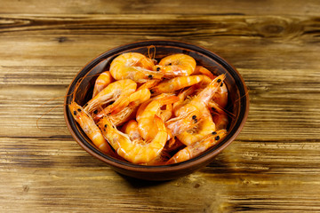 Fresh raw shrimps in a ceramic bowl on a wooden table