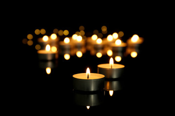Burning candles on table against dark background