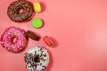 Tasty donuts and macaroons on pink background. Top view, copy space