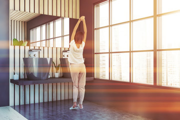 Fototapeta premium Woman in gray and wooden bathroom with sink
