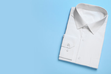Stylish white shirt on light blue background, top view with space for text. Dry-cleaning service