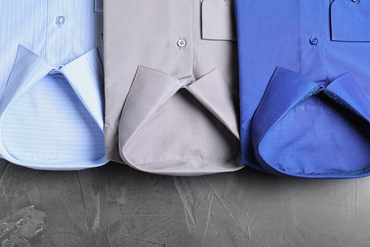 Stylish folded shirts on grey stone table, flat lay. Dry-cleaning service